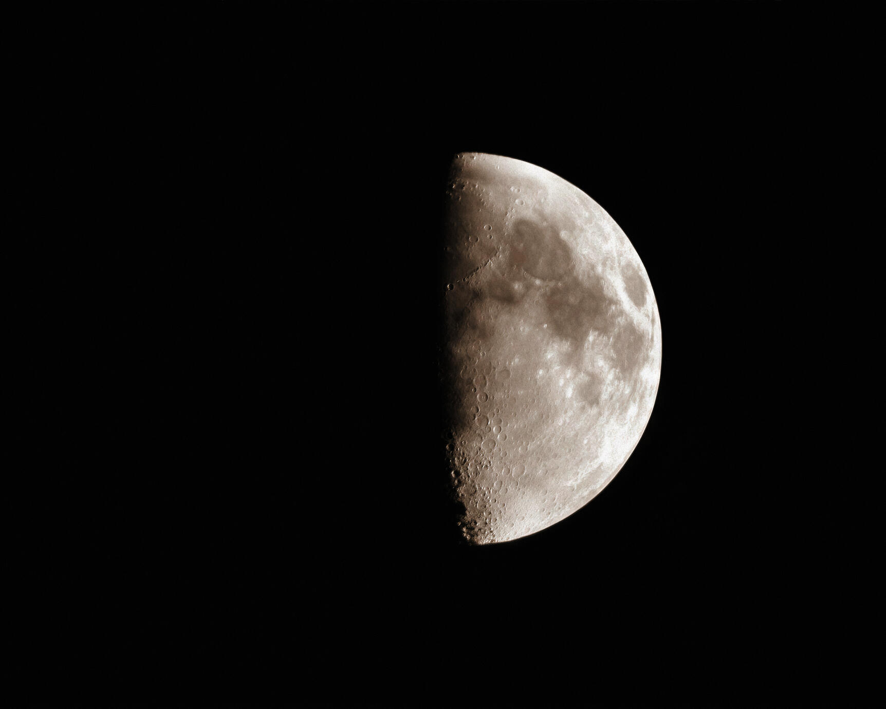 A quiet close-up of the Moon suspended against a deep black sky, revealing delicate craters and textures along its illuminated surface. Photographed in Algonquin Park, Ontario, in October 2016